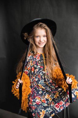 Genç kız portakal kürklü ceket ve siyah şapka Studio siyah arka plan üzerine poz