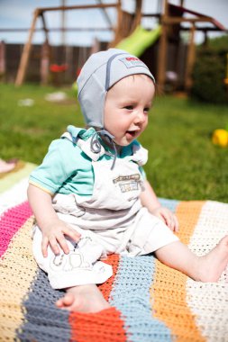 Bebek Çocuk arka bahçesinde üzerinde renkli kareli oturan 