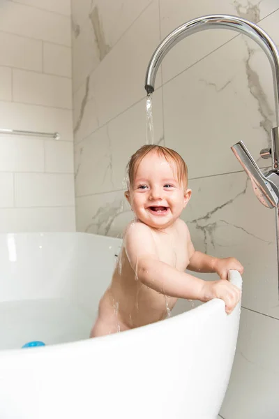 Gülümseyen bebek çocuk banyo akan altında ayakta su