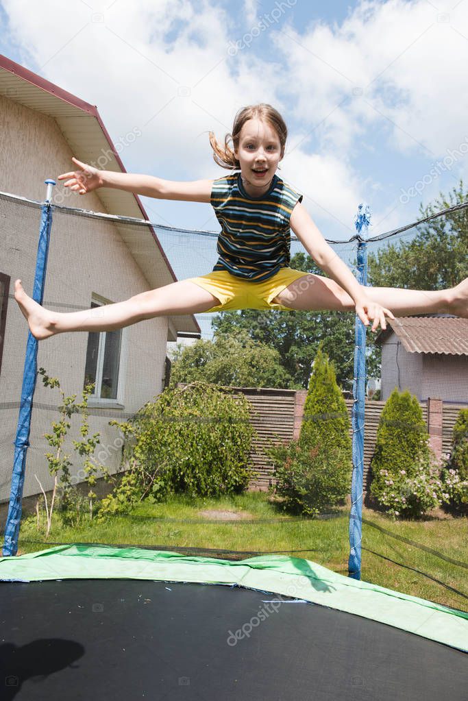 Young girl jumping on trampoline on backyard 