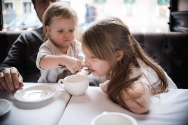 Kızlarıyla birlikte kafede oturan baba