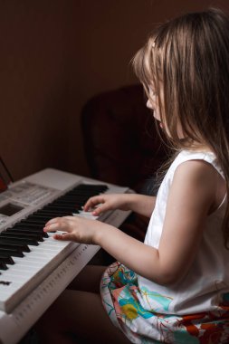 Piyano çalan uzun saçlı küçük kız.