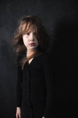 karanlık stüdyo arka plan üzerinde güneş ışığında poz sevimli küçük kız portresi, yakın çekim 