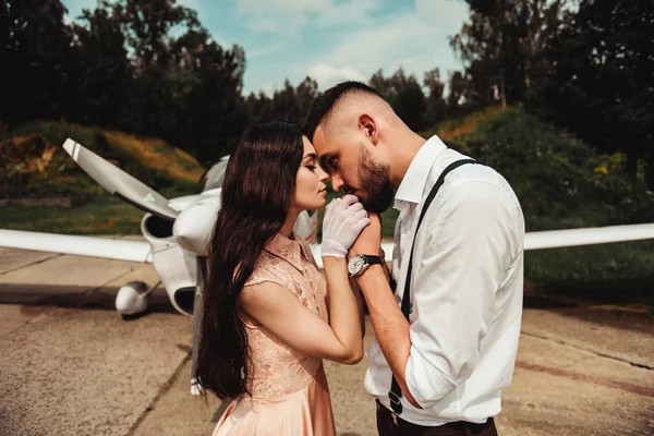 时尚的男人举行和亲吻手的优雅女人 而站在户外与飞机的背景 — 图库照片