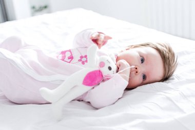 çocuk yuvasında keten kapağında yatan tavşan oyuncak ile sevimli küçük kız
