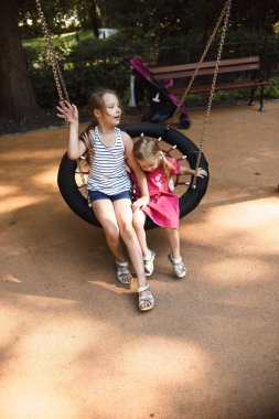 güneşli yaz gününde oyun alanında yuva salıncak oynarken birlikte vakit geçirmek kız kardeşler 
