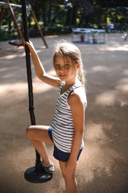güneşli yaz gününde oyun alanında disk salıncak üzerinde küçük kız salıncak 