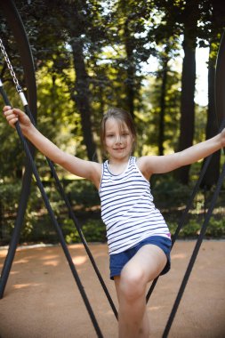 güneşli yaz gününde oyun alanında halat salıncak salıncak sırasında oynayan küçük kız 
