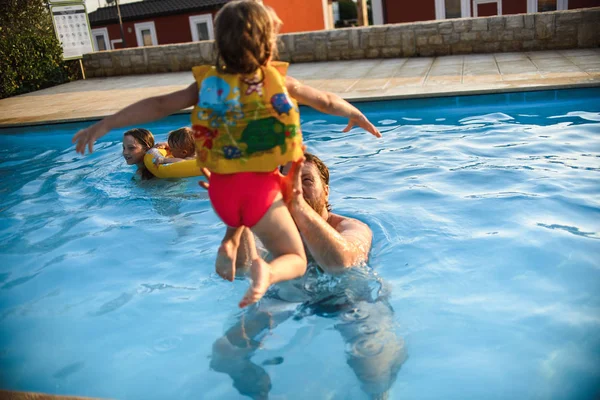 スイミングプールで遊んでいる間楽しい子供を持つ父親 — ストック写真