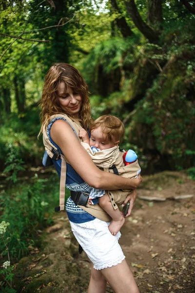 森の中を歩くスリングで赤ちゃんとママ — ストック写真