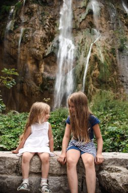 şelaleye karşı oturan kız kardeşler