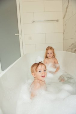 Küçük kardeşi ve kız kardeşi birlikte eğlenceli ve çekici banyo ışık banyoya sahip  