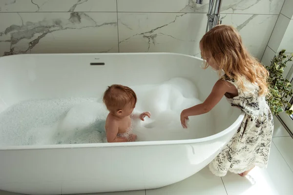 Küçük kardeşi ve kız kardeşi birlikte eğlenceli ve çekici banyo ışık banyoya sahip  