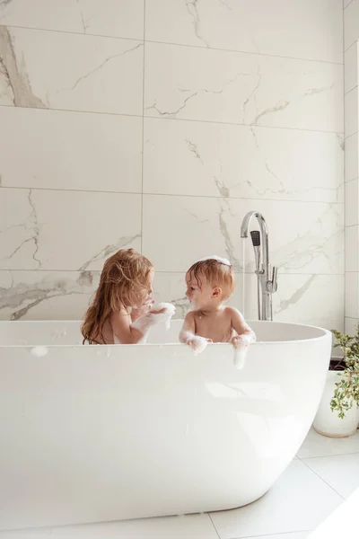 Küçük kardeşi ve kız kardeşi birlikte eğlenceli ve çekici banyo ışık banyoya sahip  