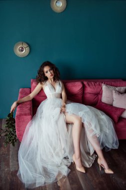 elinde pembe kanepede oturan çiçekleri ile gelinlik güzel gelin  