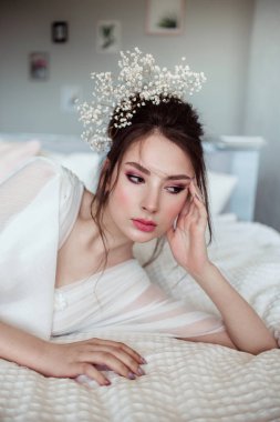 yatak odasında beyaz yatakta yatan zarif esmer gelin 