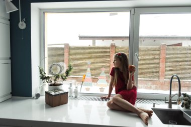 elma ile pencere yakınında oturan kız