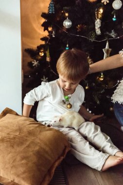 Çocuklar Noel ağacının yanında fareyle oynuyorlar.