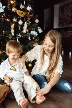 Çocuklar Noel ağacının yanında fareyle oynuyorlar.