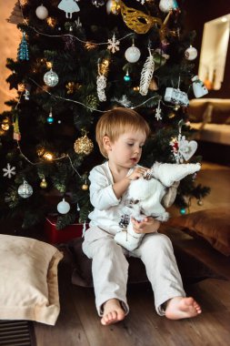 Noel ağacının yanında oyuncakları olan çocuk