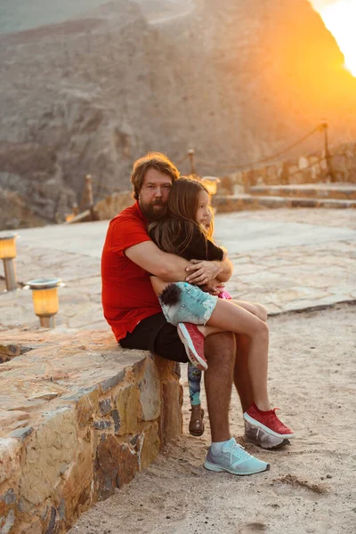 Dad hugging daughters in the mountains