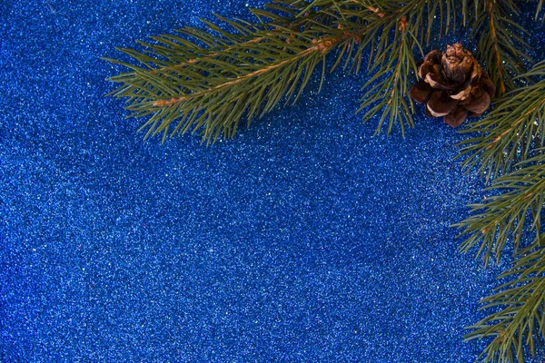 Tatil, kış ve kutlama kavramı. Noel ağacı koniler parlak mavi arka plan ve köknar dallar ile Noel ve yeni yıl kartı.