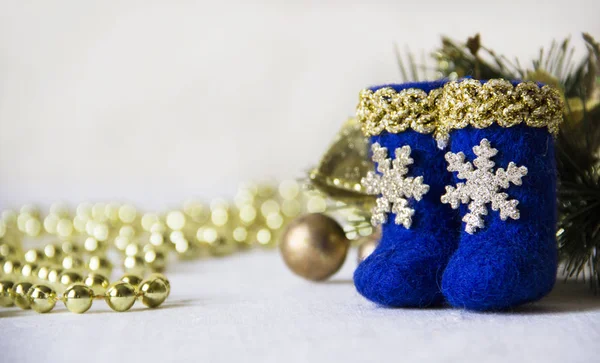 Tatil, kış ve kutlama kavramı - Noel ve yeni yıl kartı ile oyuncak parlak mavi çizmeler ile altın bir kenarlık ve bir kar tanesi, altın boncuk, ışıklar ve köknar dalı arka plan üzerinde bulanık.