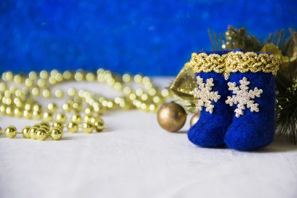 Tatil, kış ve kutlama kavramı - Noel ve yeni yıl kartı ile oyuncak parlak mavi çizmeler ile altın bir kenarlık ve bir kar tanesi, altın boncuk, ışıklar ve köknar dalı arka plan üzerinde bulanık.