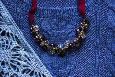Örgü ve el kavramı mavi örgü kazak ve kırmızı gerdanlık kolye yaptı. Örgü doku. Örme giyim parçası. Sonbahar, kış konsepti. Görünümü ana sayfa, yer kopyalayın, yat.