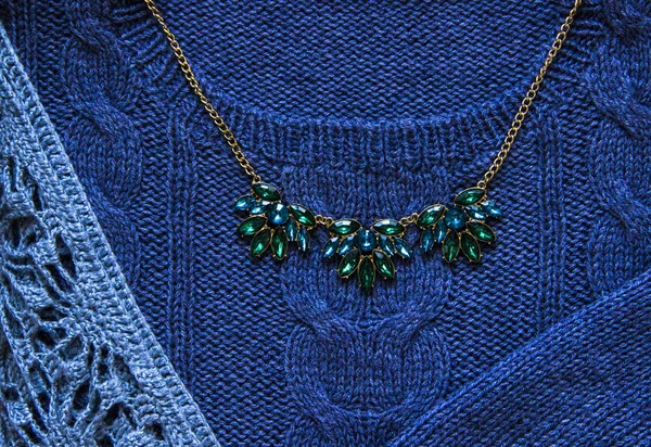 Örgü ve el kavramı mavi örgü kazak ve yeşil Kolye Altın zincir yakın çekim ile yaptı. Örgü doku. Örme giyim parçası. Sonbahar, kış konsepti. Görünümü ana sayfa, yer kopyalayın, yat.