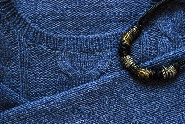 Örgü ve el kavramı mavi örgü kazak ve siyah gerdanlık yakın çekim yaptı. Örgü doku. Örme giyim parçası. Sonbahar, kış konsepti. Görünümü ana sayfa, yer kopyalayın, yat.