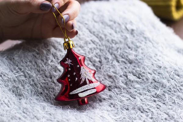 Tatil, kış ve kutlama kavram - bir Noel oyuncak bir gri karşı tutan bir kadın atkı ördü. Noel dekorasyonu. Ev dekorasyon konsepti. Yeni yıl ruh hali. 