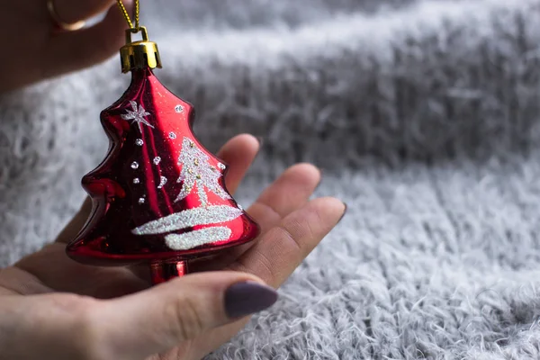 Tatil, kış ve kutlama kavram - bir Noel oyuncak gri bir arka plan üzerinde tutan bir kadın atkı ördü. Noel dekorasyonu. Ev dekorasyon konsepti. Yeni yıl ruh hali. 