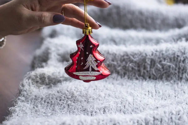 Tatil, kış ve kutlama kavram - bir Noel oyuncak gri bir arka plan üzerinde tutan bir kadın atkı ördü. Noel dekorasyonu. Ev dekorasyon konsepti. Yeni yıl ruh hali. 