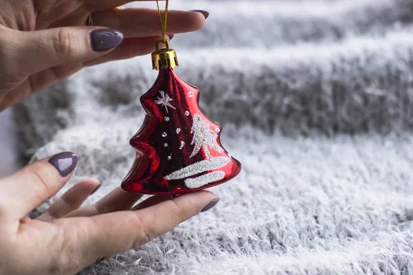 Tatil, kış ve kutlama kavram - bir Noel oyuncak gri bir arka plan üzerinde tutan bir kadın atkı ördü. Noel dekorasyonu. Ev dekorasyon konsepti. Yeni yıl ruh hali. 