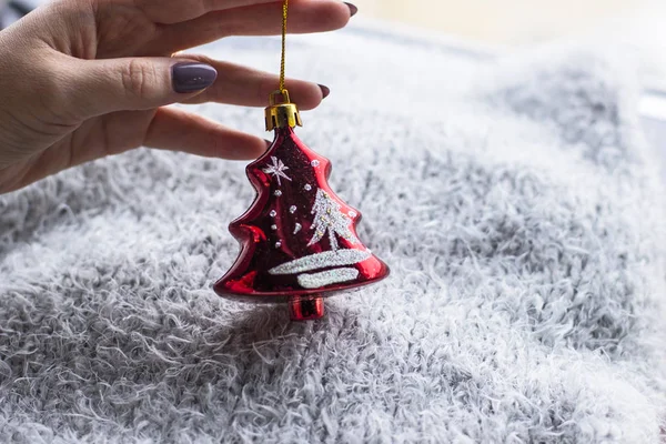 Tatil, kış ve kutlama kavram - bir Noel oyuncak gri bir arka plan üzerinde tutan bir kadın atkı ördü. Noel dekorasyonu. Ev dekorasyon konsepti. Yeni yıl ruh hali. 