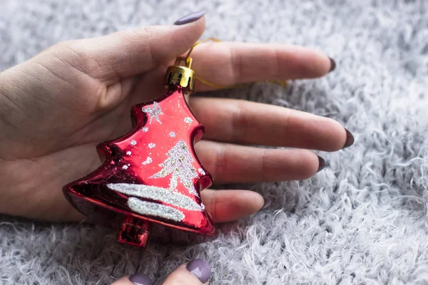 Tatil, kış ve kutlama kavram - bir Noel oyuncak gri bir arka plan üzerinde tutan bir kadın atkı ördü. Noel dekorasyonu. Ev dekorasyon konsepti. Yeni yıl ruh hali. 