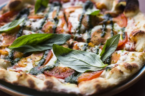 Pizza Margarita on wooden table background, top view. Pizza Margarita with Tomatoes, Fresh Basil, Mozzarella Cheese, Pepper and Spices close up. Sliced Italian Pizza. Pizza Margherita or Margarita.