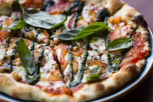 Pizza Margarita on wooden table background, top view. Pizza Margarita with Tomatoes, Fresh Basil, Mozzarella Cheese, Pepper and Spices close up. Sliced Italian Pizza. Pizza Margherita or Margarita.