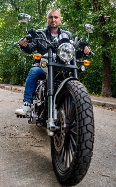 Kyiv 'deki Geon Daytona motosikletinde dövmeli, sakallı ve bilezikli genç yakışıklı bir adam.