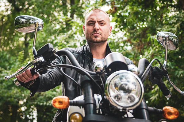 Kyiv 'deki Geon Daytona motosikletinde dövmeli, sakallı ve bilezikli genç yakışıklı bir adam.