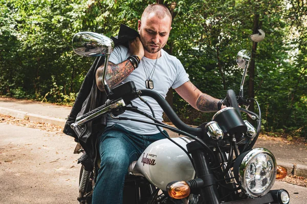 Kyiv 'deki Geon Daytona motosikletinde dövmeli, sakallı ve bilezikli genç yakışıklı bir adam.