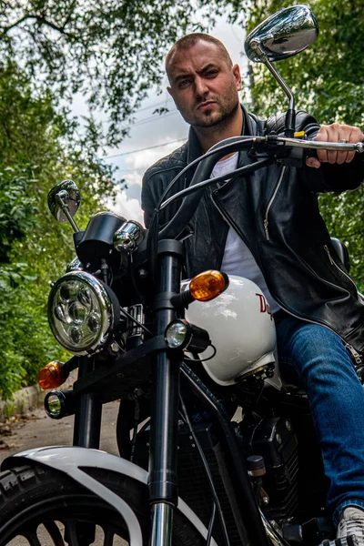 Kyiv 'deki Geon Daytona motosikletinde dövmeli, sakallı ve bilezikli genç yakışıklı bir adam.