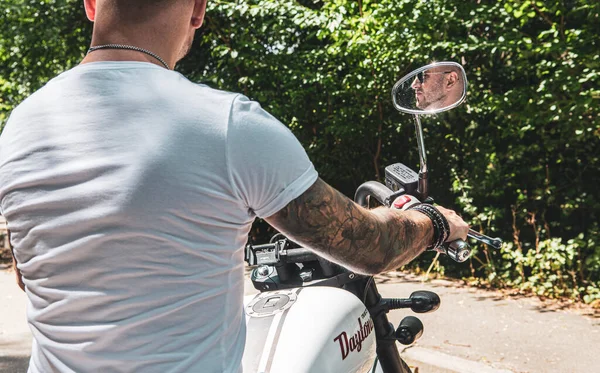 Kyiv 'deki Geon Daytona motosikletinde dövmeli, sakallı ve bilezikli genç yakışıklı bir adam.