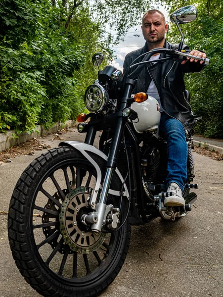 Kyiv 'deki Geon Daytona motosikletinde dövmeli, sakallı ve bilezikli genç yakışıklı bir adam.