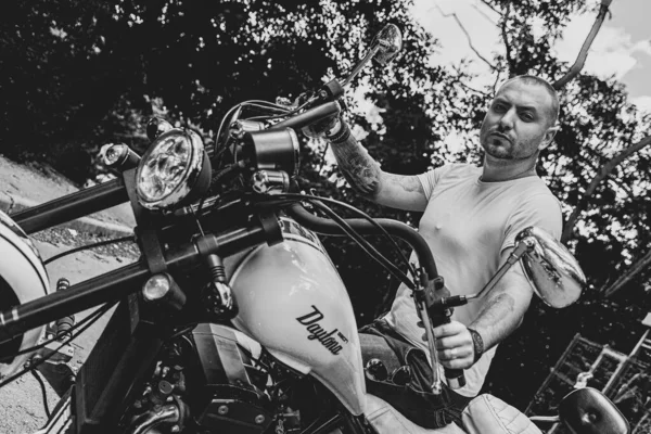 Kyiv 'deki Geon Daytona motosikletinde dövmeli, sakallı ve bilezikli genç yakışıklı bir adam.