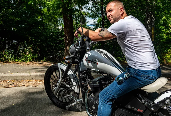 Kyiv 'deki Geon Daytona motosikletinde dövmeli, sakallı ve bilezikli genç yakışıklı bir adam.