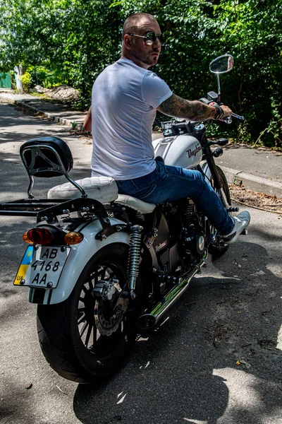 Kyiv 'deki Geon Daytona motosikletinde dövmeli, sakallı ve bilezikli genç yakışıklı bir adam.