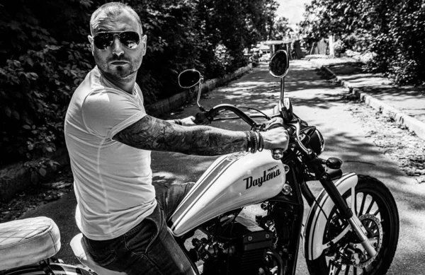 Kyiv 'deki Geon Daytona motosikletinde dövmeli, sakallı ve bilezikli genç yakışıklı bir adam.