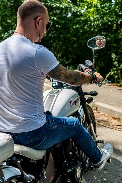 Kyiv 'deki Geon Daytona motosikletinde dövmeli, sakallı ve bilezikli genç yakışıklı bir adam.